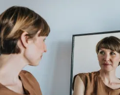 Thoughtful woman looking at reflection in mirror