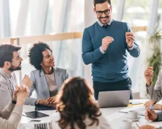 Male standing in front of computer addressing staff