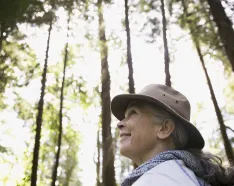 Smiling woman wearing a hat walking in the forest