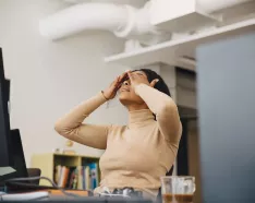 Frustrated woman at the office with hands on head