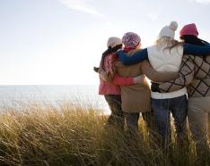 four women in fall clothing hugging