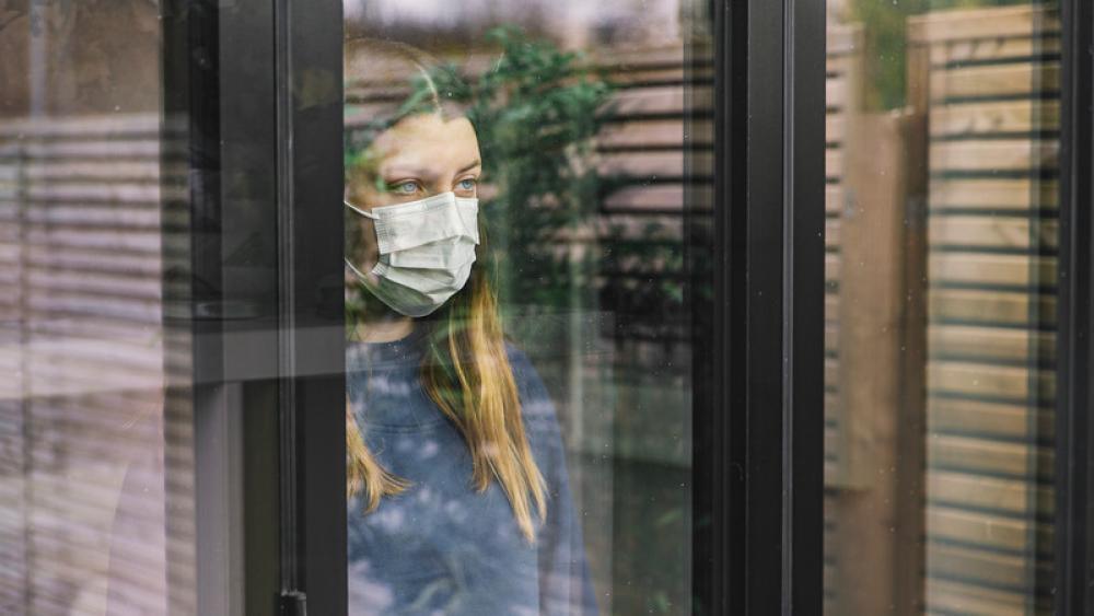 woman wearing mask looking out window