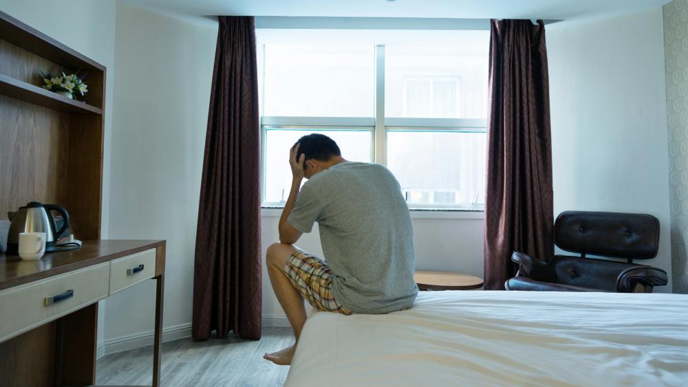 Man sitting on bed with head in hands