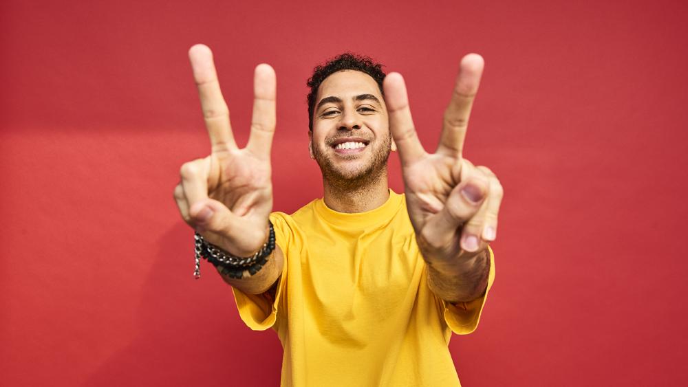 Man holding up peace sign to the camera