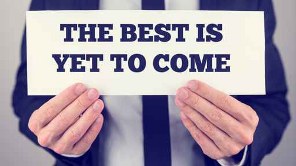 Man holding a sign that says The Best Is Yet To Come