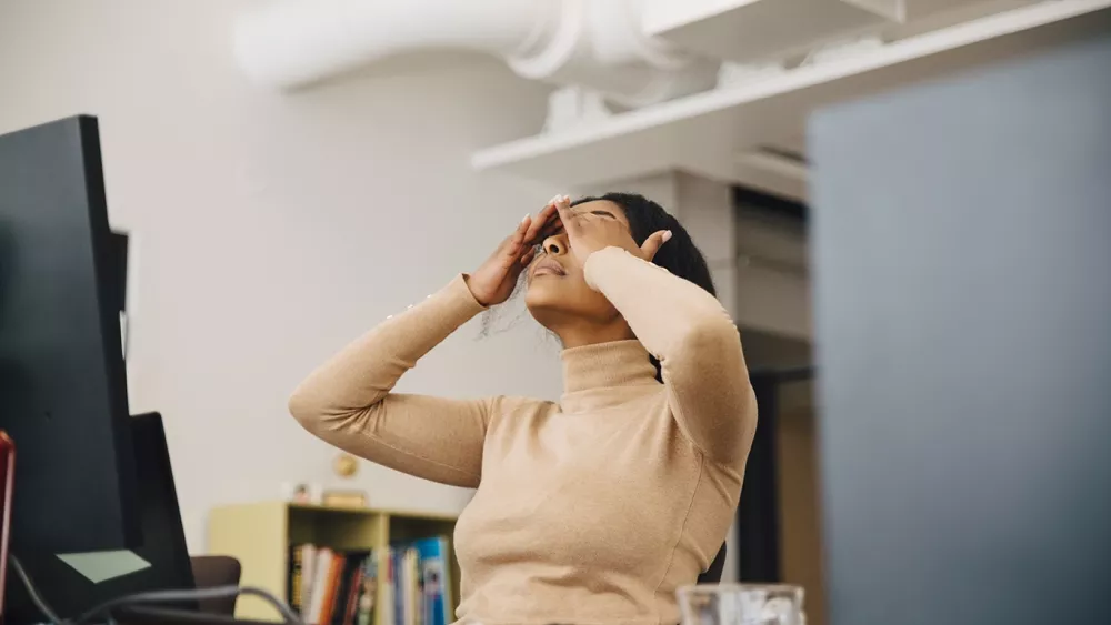 Frustrated woman at the office with hands on head